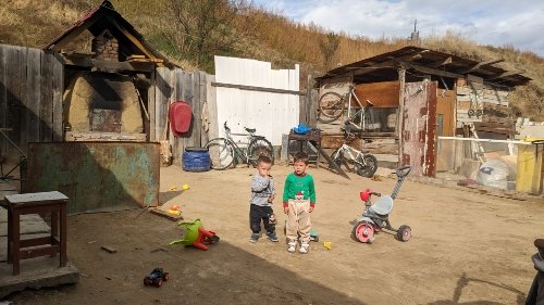 Cristina's grandchildren play in the sparse yard of her modest home
